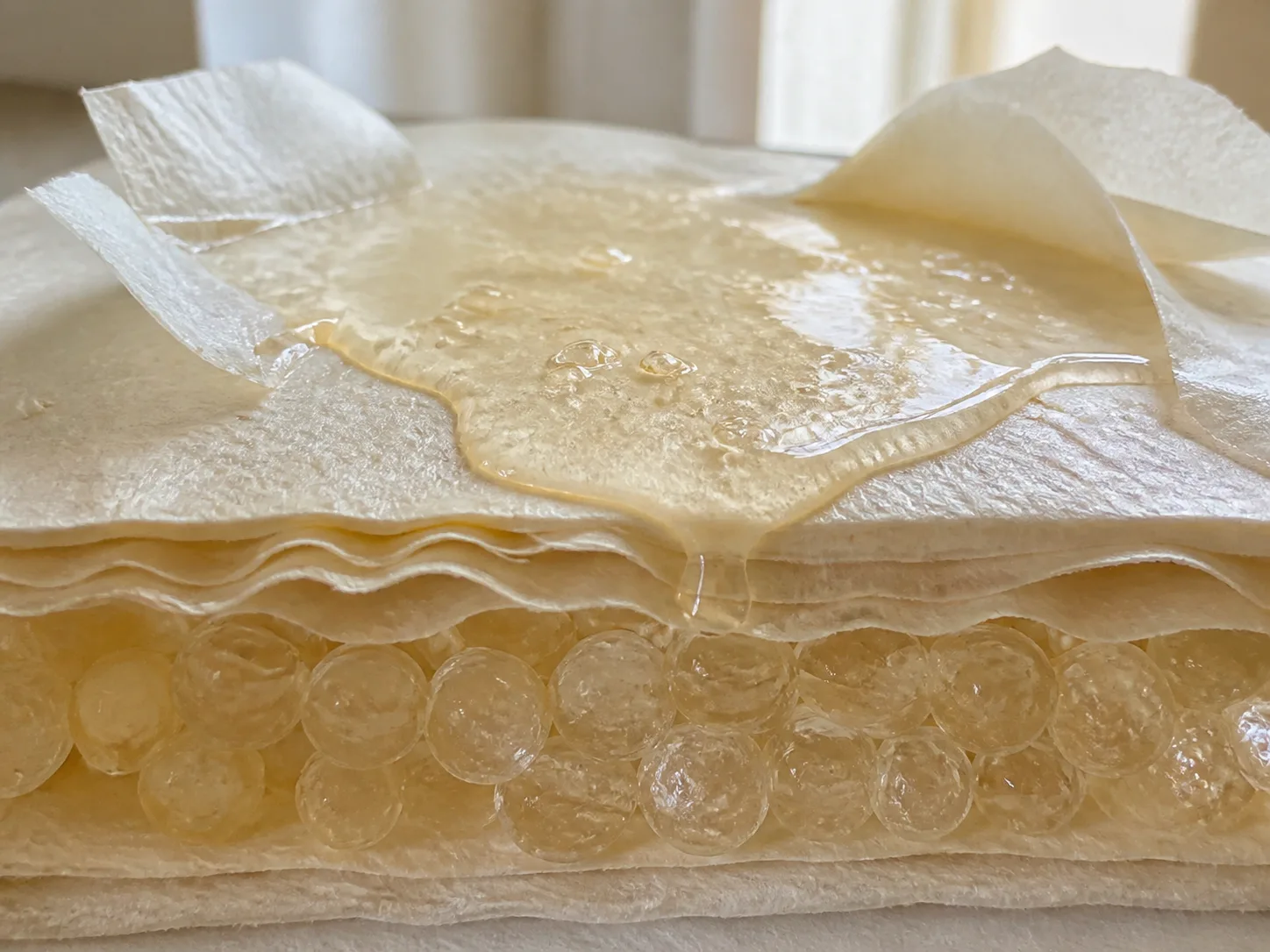Miniature diorama showing a water-based formula spreading across a skin-like surface